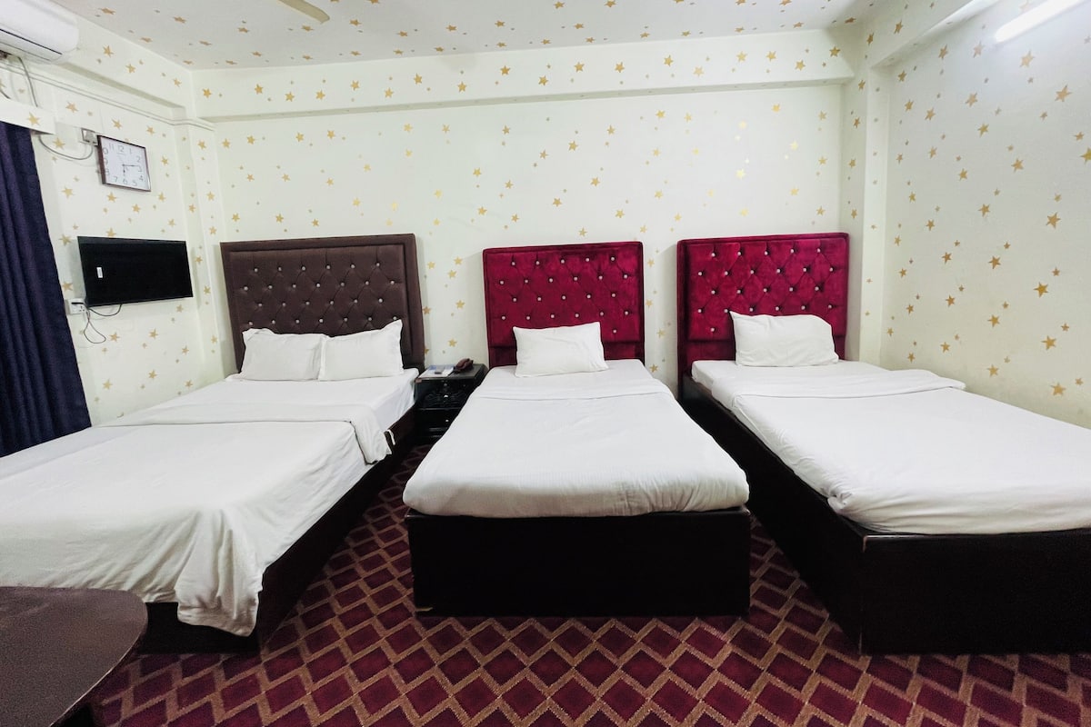 A hotel room with three beds, a ceiling fan, and star-patterned walls.