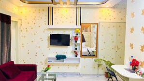 Un salon avec un canapé rouge, un téléviseur fixé au mur, une console blanche et un miroir.