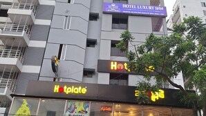 Un immeuble à plusieurs étages portant l’enseigne « HÔTEL LUXE », un restaurant de type « Hotplate » et un magasin appelé « WAFFLE TIME ».