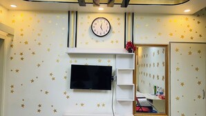 Une pièce avec un téléviseur fixé au mur, une horloge et un miroir.
