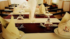 Une table à manger dressée avec des serviettes blanches, des couverts en argent et de la verrerie transparente.