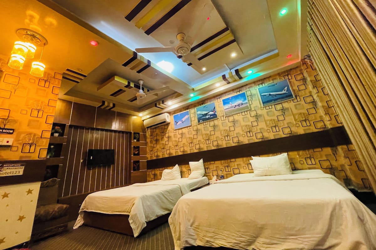 A hotel room with two beds, a reception desk, and a wall with framed pictures.