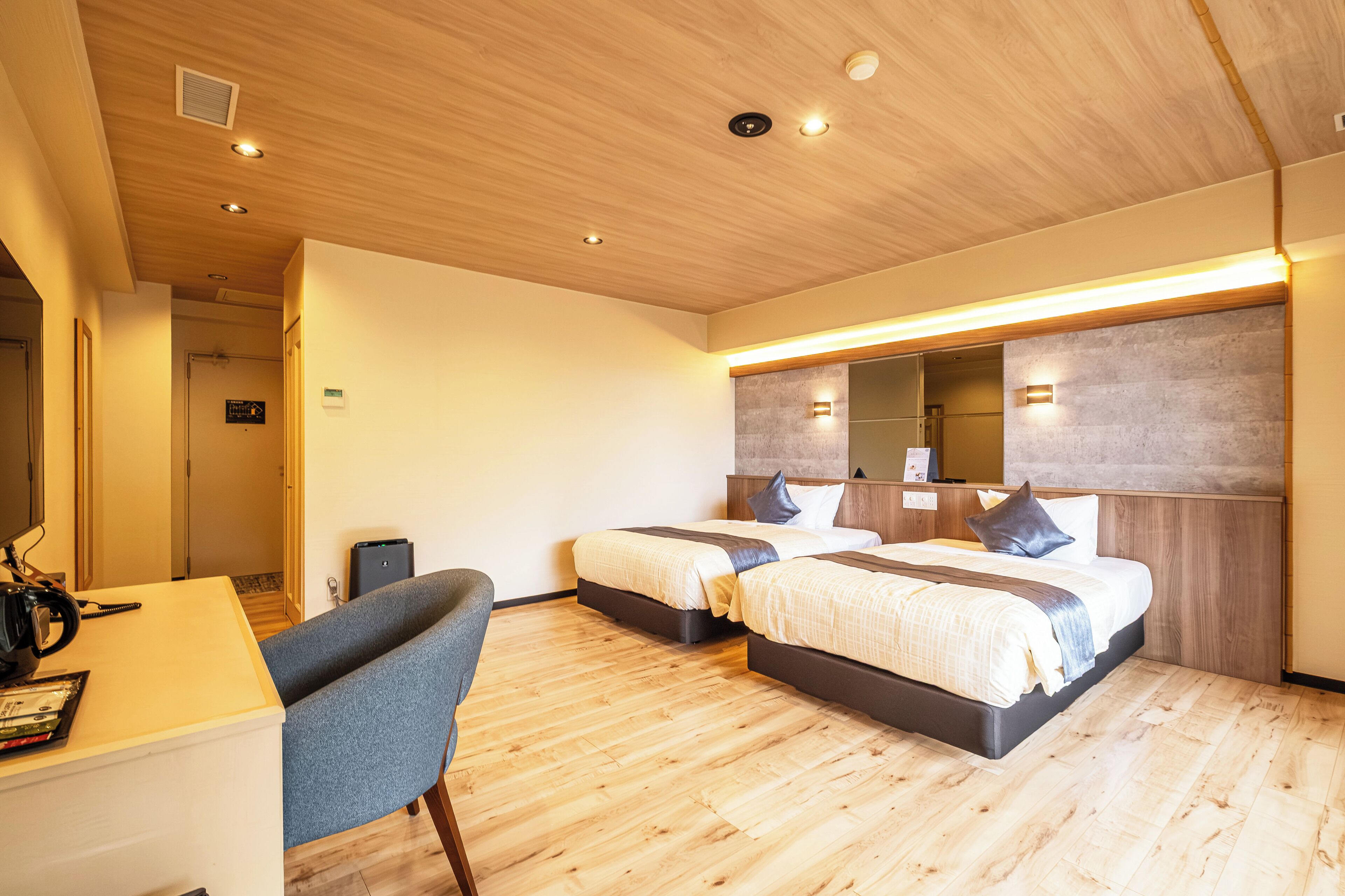 Een moderne hotelkamer met twee bedden, een bureau en een stoel.