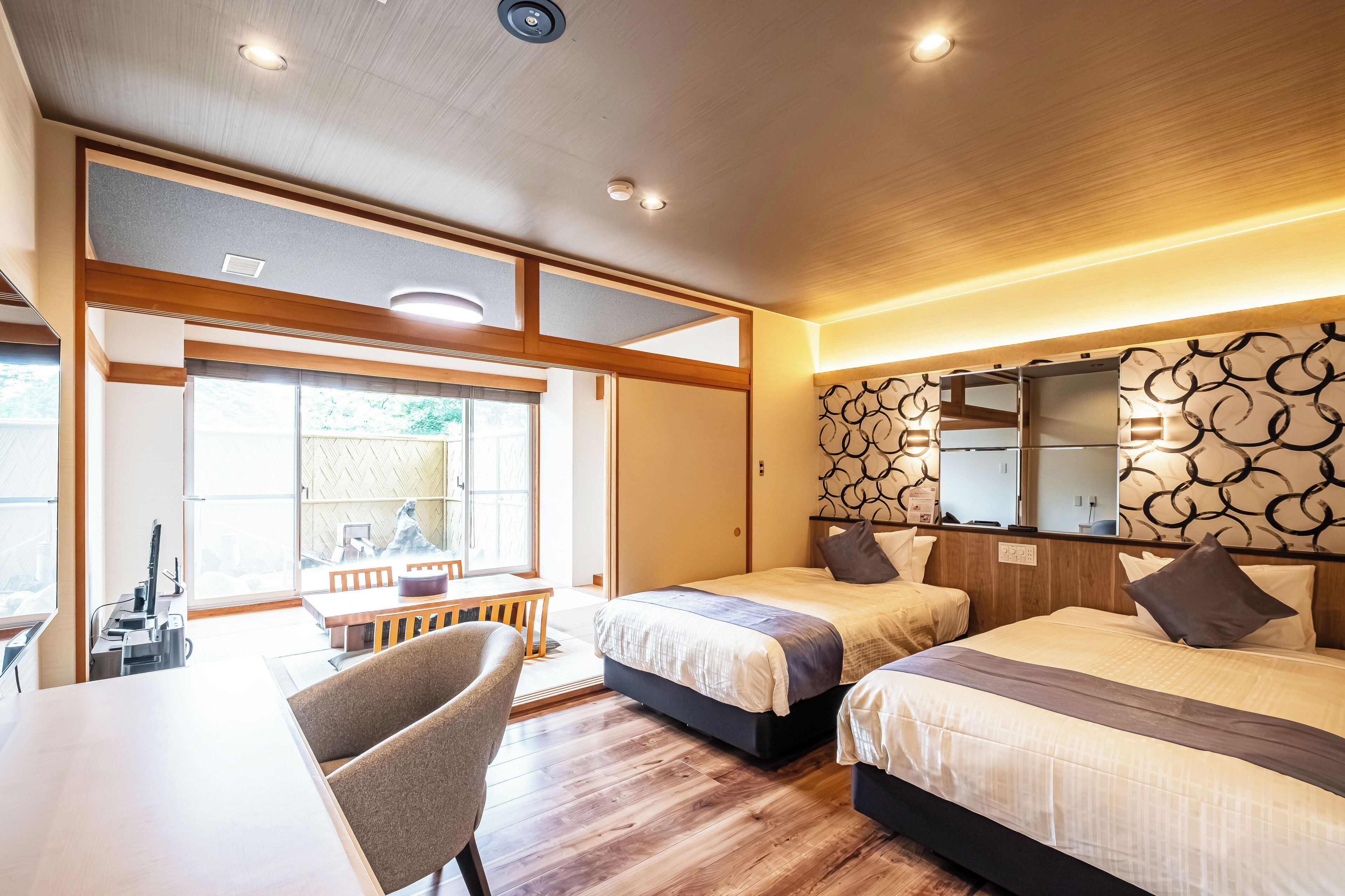 Een hotelkamer met twee bedden, een zithoek en een groot raam.