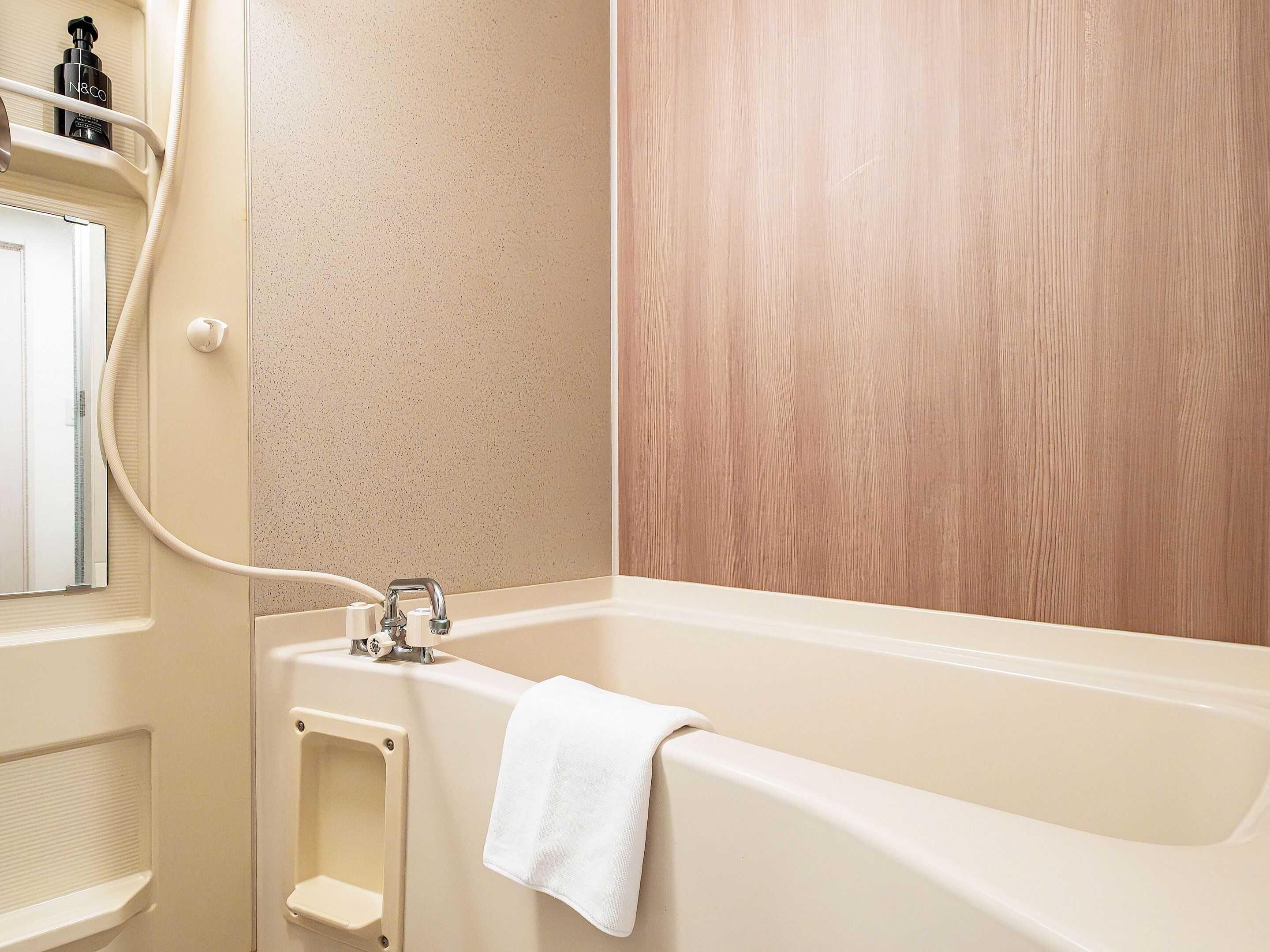 A bathroom with a bathtub, a towel hanging on the side, and a shower area.