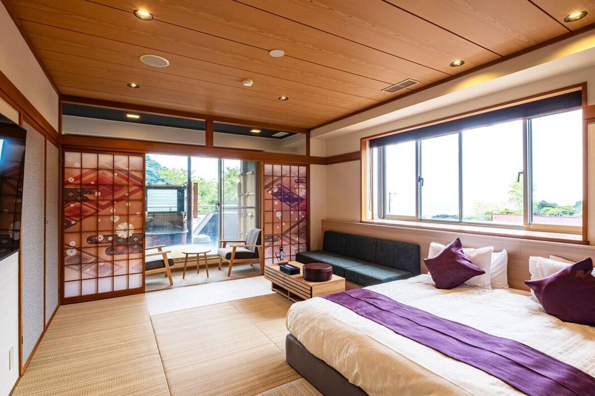 Una habitación de hotel moderna con una cama grande, zona de estar y vistas al exterior.
