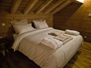 Habitación con paneles de madera, cama, almohadas y toallas dobladas con cuidado.