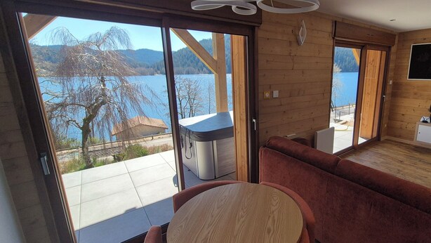Une cabane moderne dotée d’une grande porte-fenêtre coulissante donnant sur un balcon, d’un coin salon confortable et d’une petite kitchenette.
