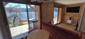 A modern cabin with a large sliding glass door leading to a balcony, a cozy seating area, and a small kitchenette. - L'Or du Lac (Gérardmer)