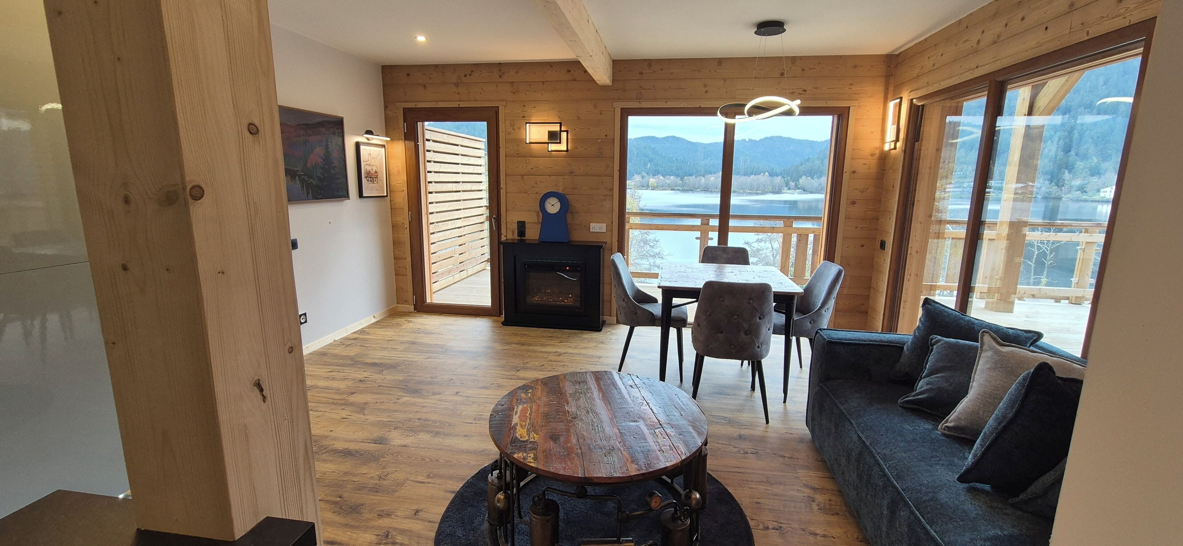 A cozy room with a wooden floor, a dining table with chairs, a sofa, and a fireplace.