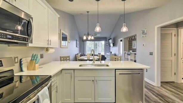 A modern kitchen with white cabinets, stainless steel appliances, and pendant lighting. - Good Vibes on the Green | Bright, Airy 2BR River Oaks Stay (Myrtle Beach)