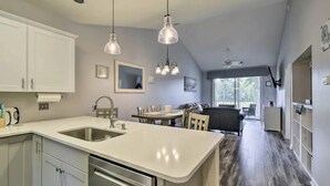 A modern kitchen with white cabinets, a double sink, and pendant lighting. - Good Vibes on the Green | Bright, Airy 2BR River Oaks Stay (Myrtle Beach)