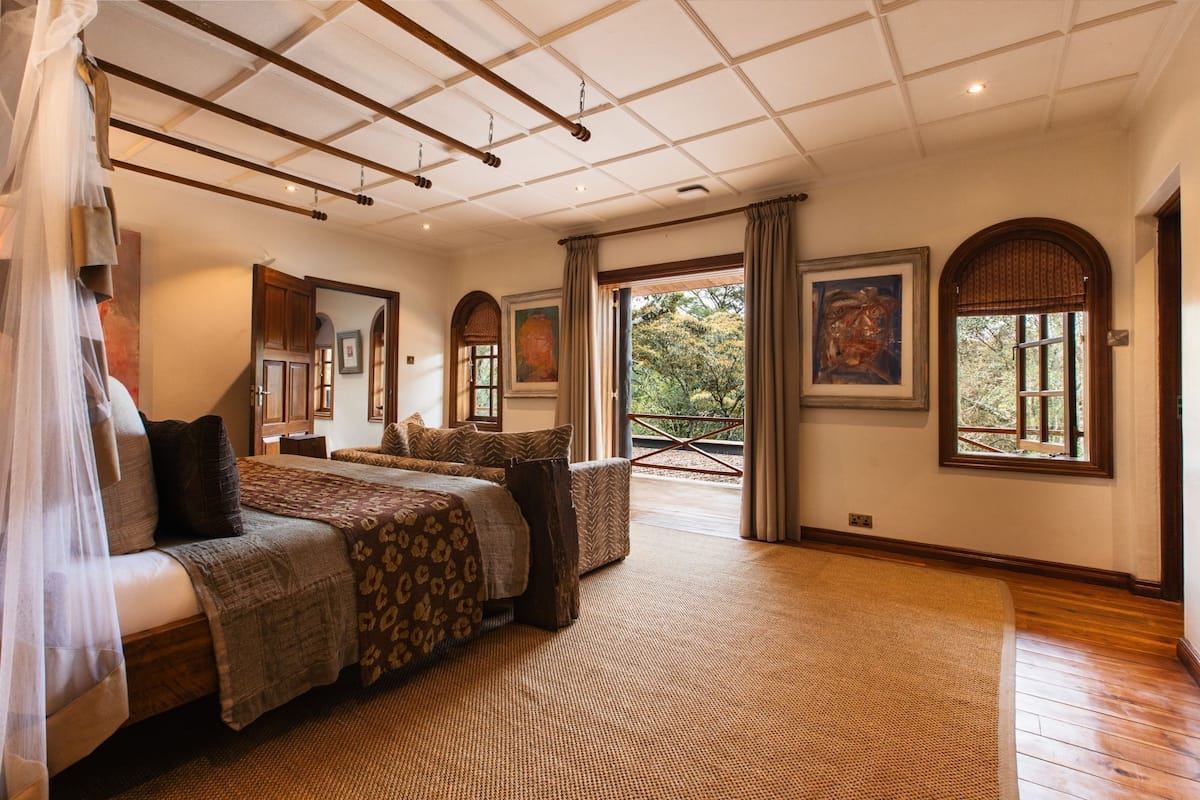A spacious bedroom with a large bed, two smaller beds, a view of the outdoors, and a ceiling with exposed beams.