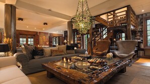 Een ruime woonkamer met een grote houten salontafel, een comfortabele bank en een bijzondere kroonluchter.