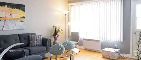 Una sala de estar moderna con un sofá gris, una mesa de centro de vidrio y un jarrón decorativo.
