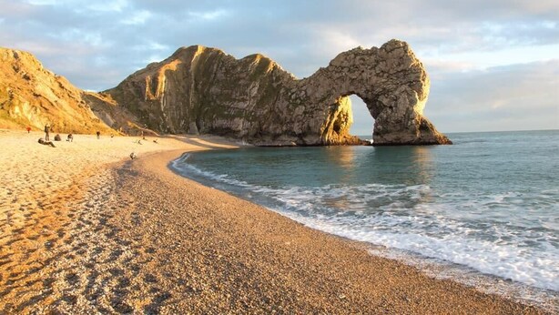 A beach with a natural rock arch formation.