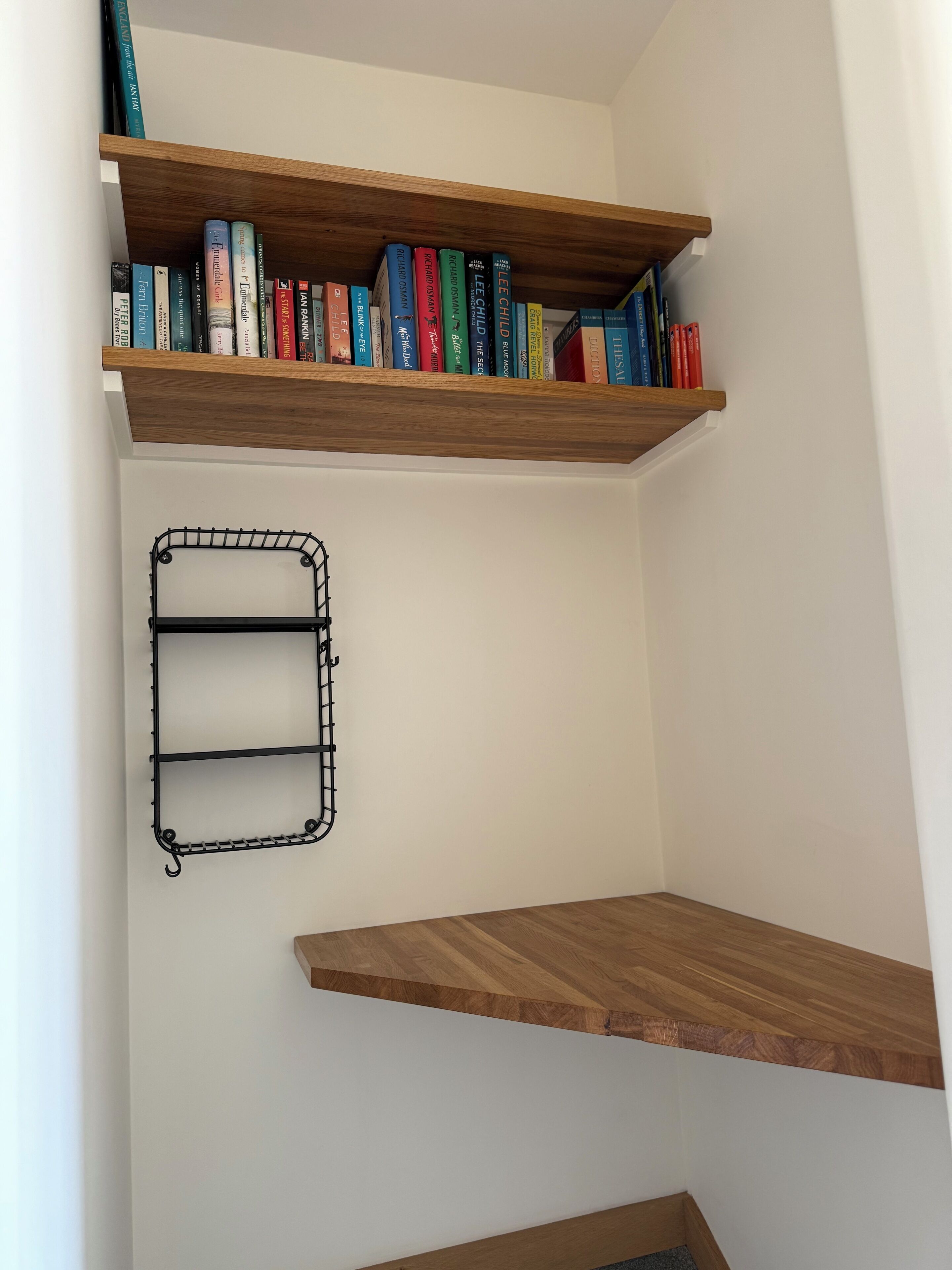 A room with two wooden shelves filled with books and a black metal shelf unit.