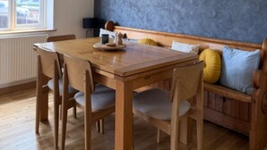 A dining area with a wooden table and chairs, a bench with cushions, and a blue textured wall.