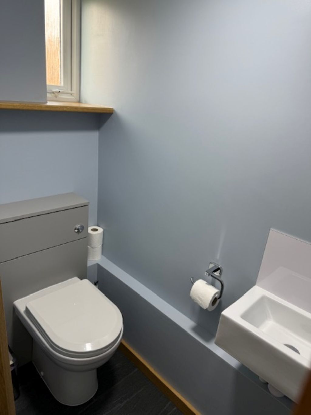 Un bagno moderno e compatto con il water, un bidet e uno scaffale sopra il water.