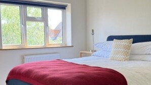 A bedroom with a bed, a window, and a nightstand.
