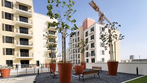 Eine Dachterrasse mit Blumentöpfen, einer Sitzbank und Blick auf angrenzende Gebäude.