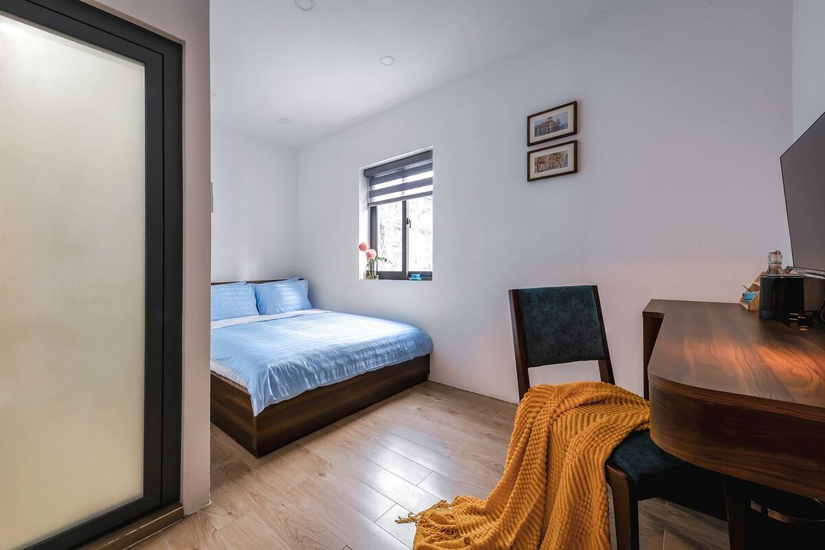 A bedroom with a bed, a window, a chair, and a desk.