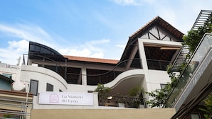 A modern building with a curved facade, a sign reading "La Maison de Lynn," and a red-tiled roof. - Lynn by La Doma Express (Ho Chi Minh City)