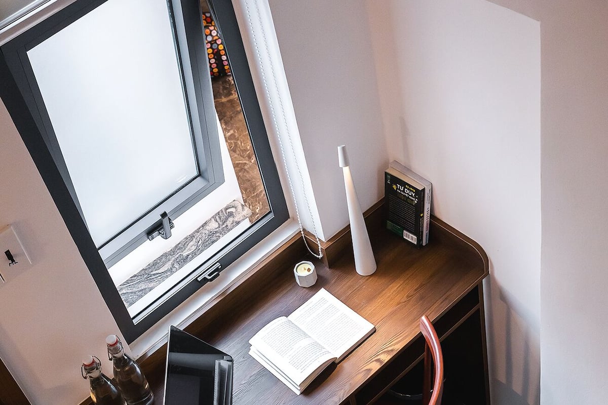 A small, modern office space with a wooden desk, a chair, a computer, and a window with blinds.