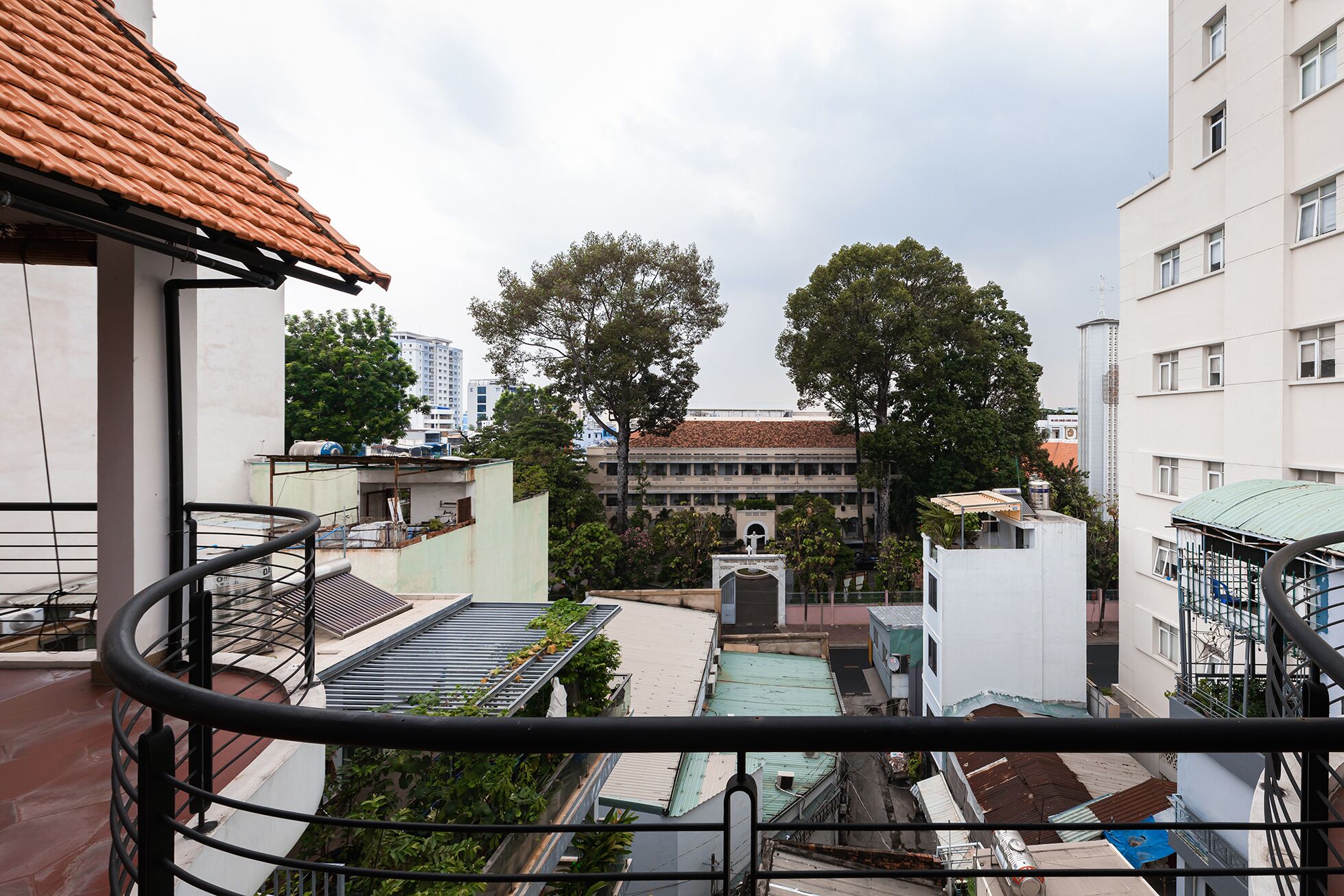 A view from a balcony overlooking a courtyard with buildings, trees, and a water tower.