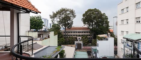 A view from a balcony overlooking a courtyard with buildings, trees, and a water tower.