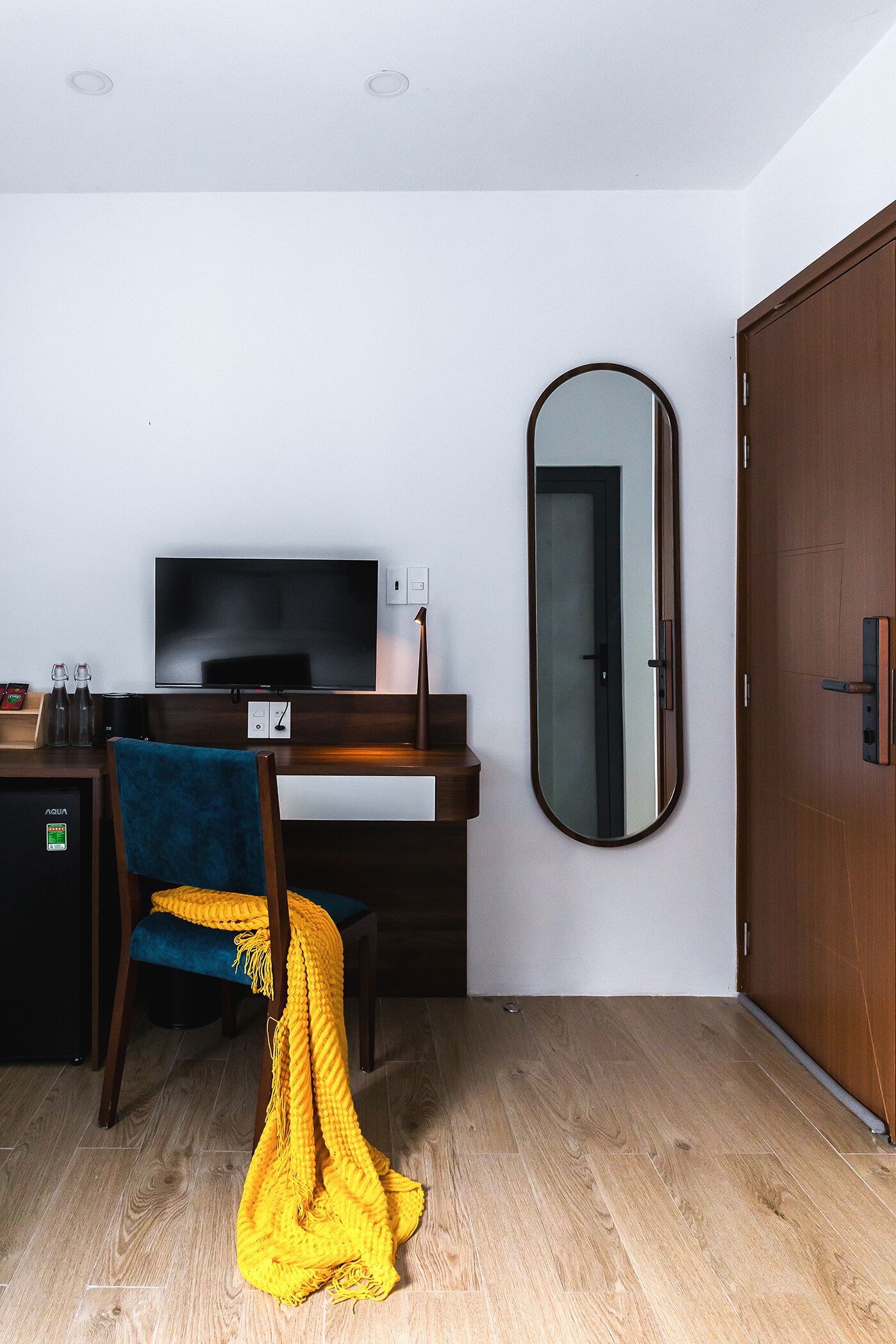 Ein Zimmer mit einem Holztisch, einem Fernseher, einem Spiegel und einem Kleiderschrank.