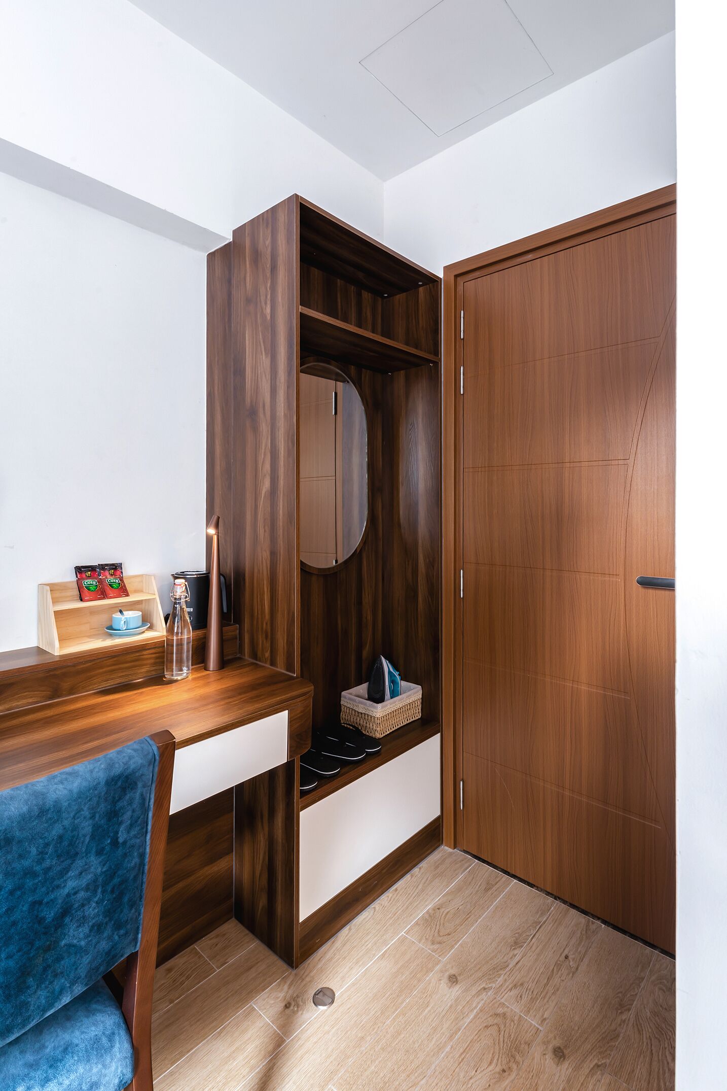 Une pièce de taille modeste, comprenant un bureau en bois, une chaise, une armoire et une petite étagère avec quelques objets.