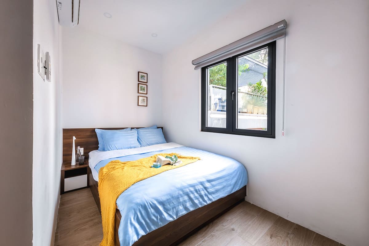 A bedroom with a bed, a nightstand, a window, and a door.