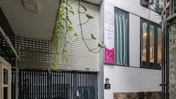 A modern building with a stone facade, a gated entrance, and a sign indicating 'La Maison de Lynn'.