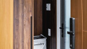 A wooden wardrobe with a hanging rack and a laundry basket labeled "laundry". - Lynn by La Doma Express (Ho Chi Minh City)