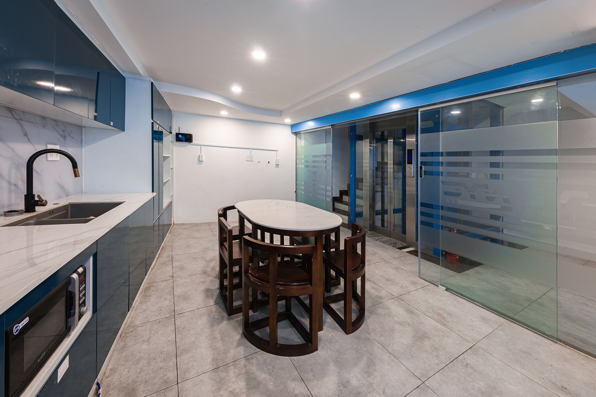 A modern kitchen with a marble countertop, a built-in oven, and a dining area with a round table and chairs.