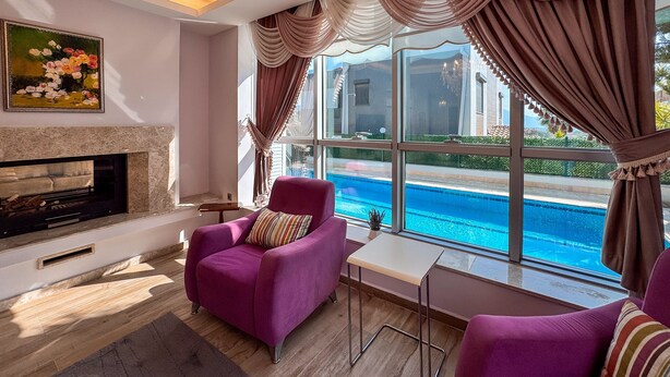 A living room with a fireplace, a pool view, and purple furniture.