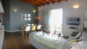 A modern living room with a dining area, a sofa, a TV, and a sliding glass door leading to an outdoor area. - CasaFranka Lake Garda (Toscolano Maderno). Quiet location and exceptional view (Toscolano Maderno)