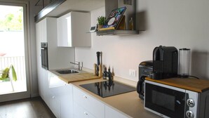 A modern kitchen with white cabinets, a wooden countertop, a microwave, a coffee maker, and a small shelf with a plant and a picture frame. - CasaFranka Lake Garda (Toscolano Maderno). Quiet location and exceptional view (Toscolano Maderno)