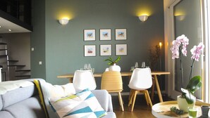 A modern living room with a grey sofa, a dining table with chairs, and a small round table with a plant and a vase. - CasaFranka Lake Garda (Toscolano Maderno). Quiet location and exceptional view (Toscolano Maderno)