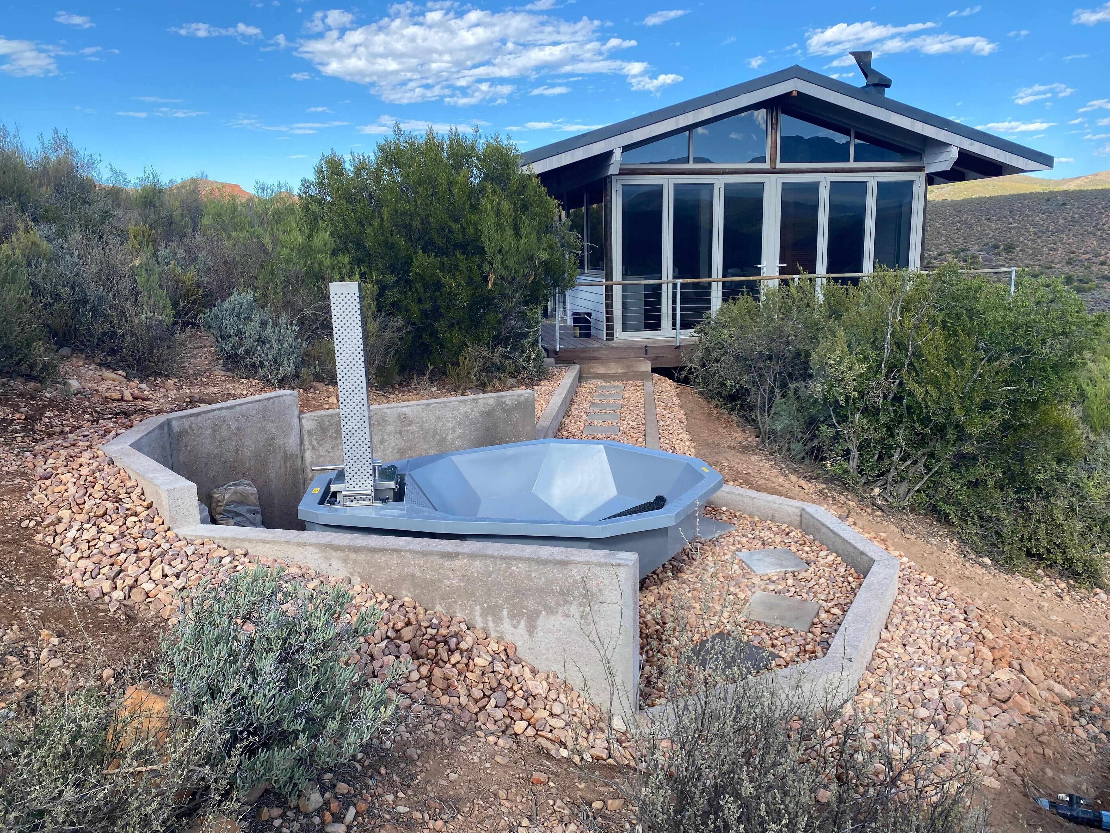 Una casa moderna con jacuzzi en un jardín ajardinado.