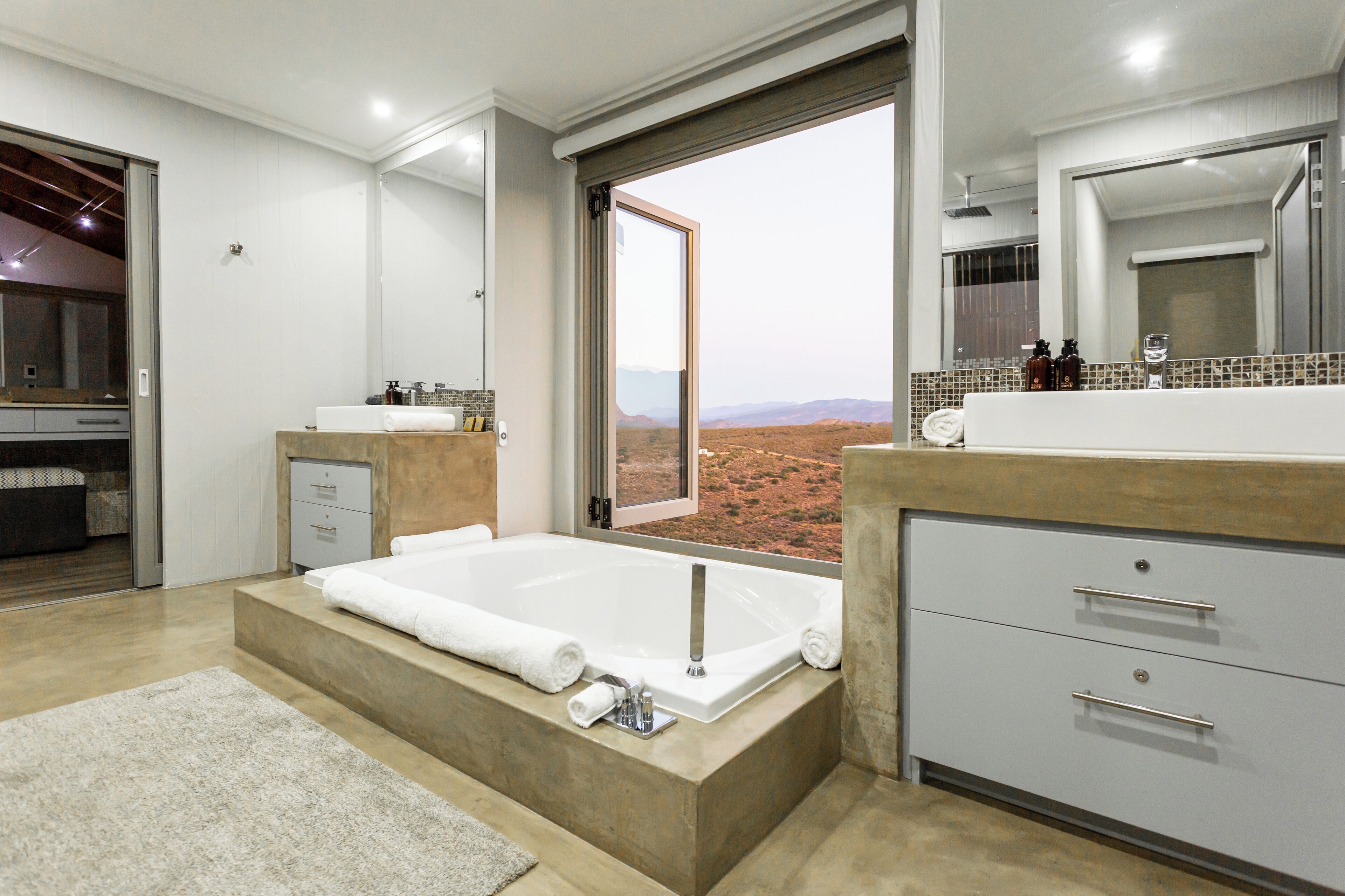 A modern bathroom with a large bathtub, a shower, and a vanity with a mirror.