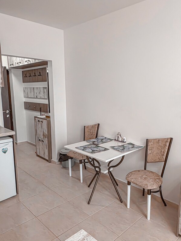 A dining area with a white table, four chairs, and a cabinet with shelves.