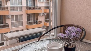 Un balcon avec une table en verre, un pot de fleurs et une chaise.