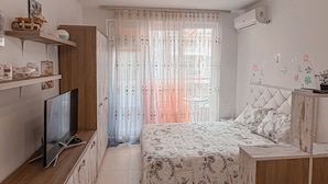 Une chambre à coucher avec un lit, une télévision, une armoire en bois et un ventilateur de plafond.