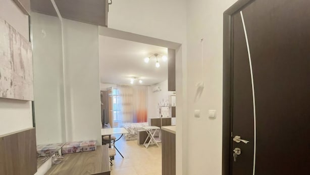 Une chambre d’hôtel avec un lit, un bureau, une chaise, une armoire et une salle de bain visible à travers une porte ouverte.