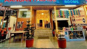 A hotel named Aangan Palace with a modern glass facade, a visible entrance, and a sign indicating restaurant and rooms. - Aangan Palace (Udaipur)