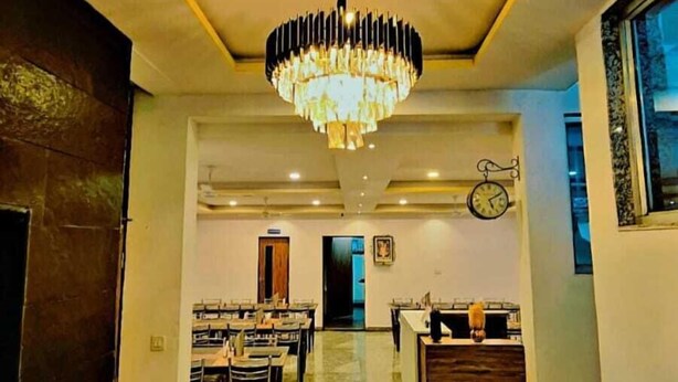 A hotel lobby with a chandelier, a reception desk, and a dining area. - Aangan Palace (Udaipur)