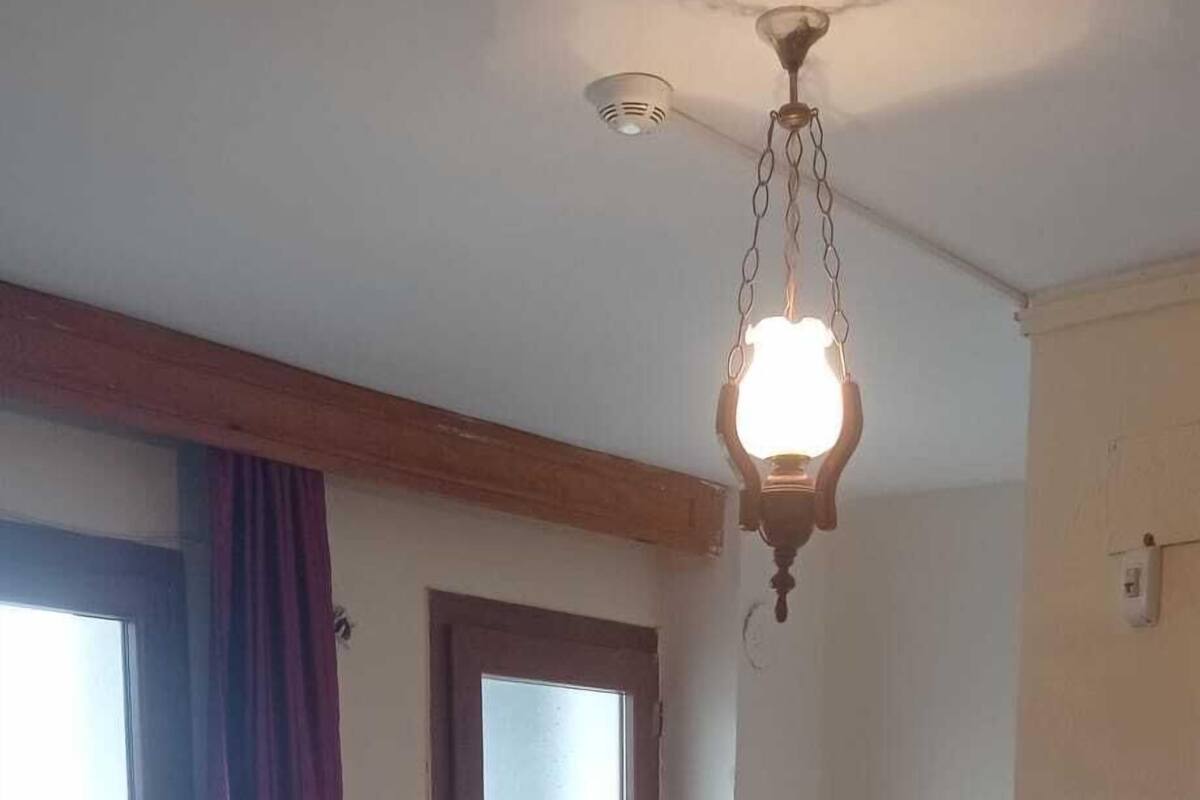 Una camera da letto con un grande letto, un trave in legno a soffitto, una lampada a sospensione e una porta che dà sull'esterno.