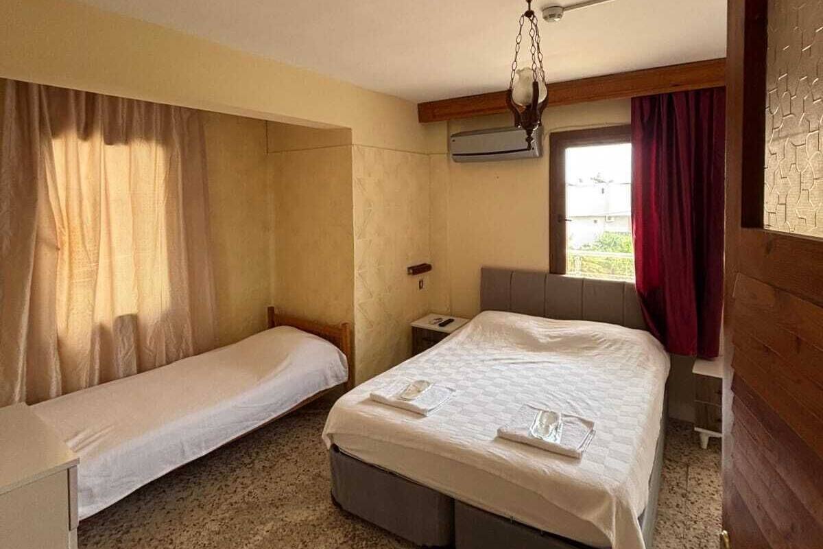 Una stanza con due letti, un tavolino, una sedia e un lampadario.